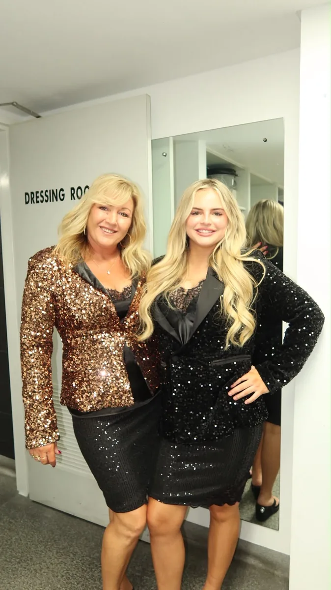Two performers in sequined blazers posing backstage